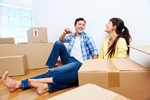 Young couple sitting among boxes in their new home