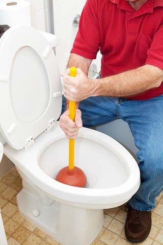 Man using a plunger to unclog a toilet.